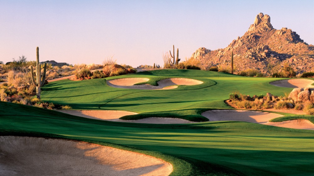 A golf green at Troon North with desert and mountains behind it